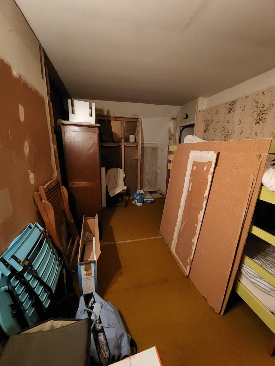 Salle de rangement encombrée avec meubles, planches et désordre.