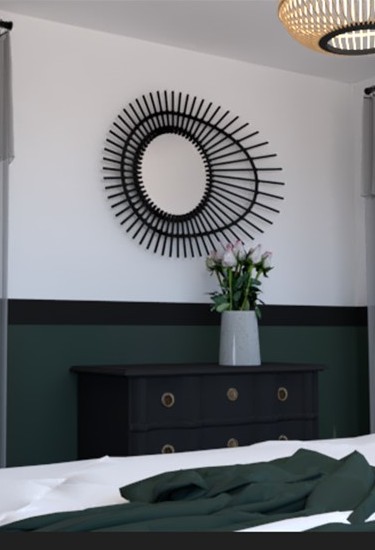Miroir rond avec cadre en rayons, vase de fleurs sur un meuble noir dans une chambre moderne.