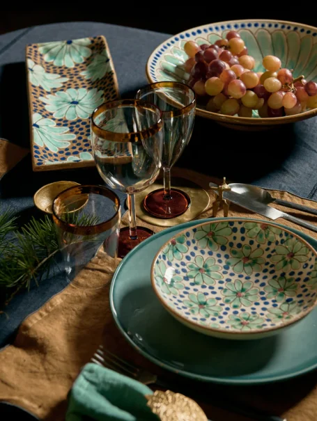 Assiette décorée, verres, fruits, et serviette sur une table élégamment dressée.