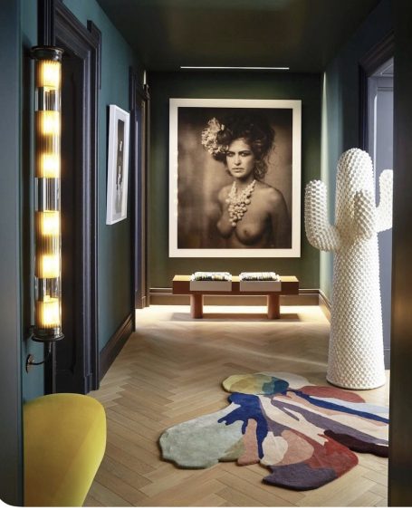 Couloir moderne avec une œuvre encadrée, sculpture et tapis coloré au sol.