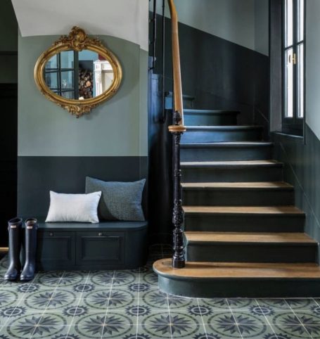 Escalier avec miroiterie dorée, banc, coussins et carrelage décoratif.